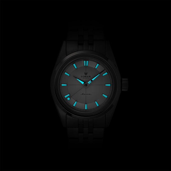 Lorier Astra automatic watch in darkness showing Superluminova lume on hands and dial glowing against black background.
