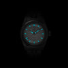 Lorier Astra automatic watch in darkness showing Superluminova lume on hands and dial glowing against black background.