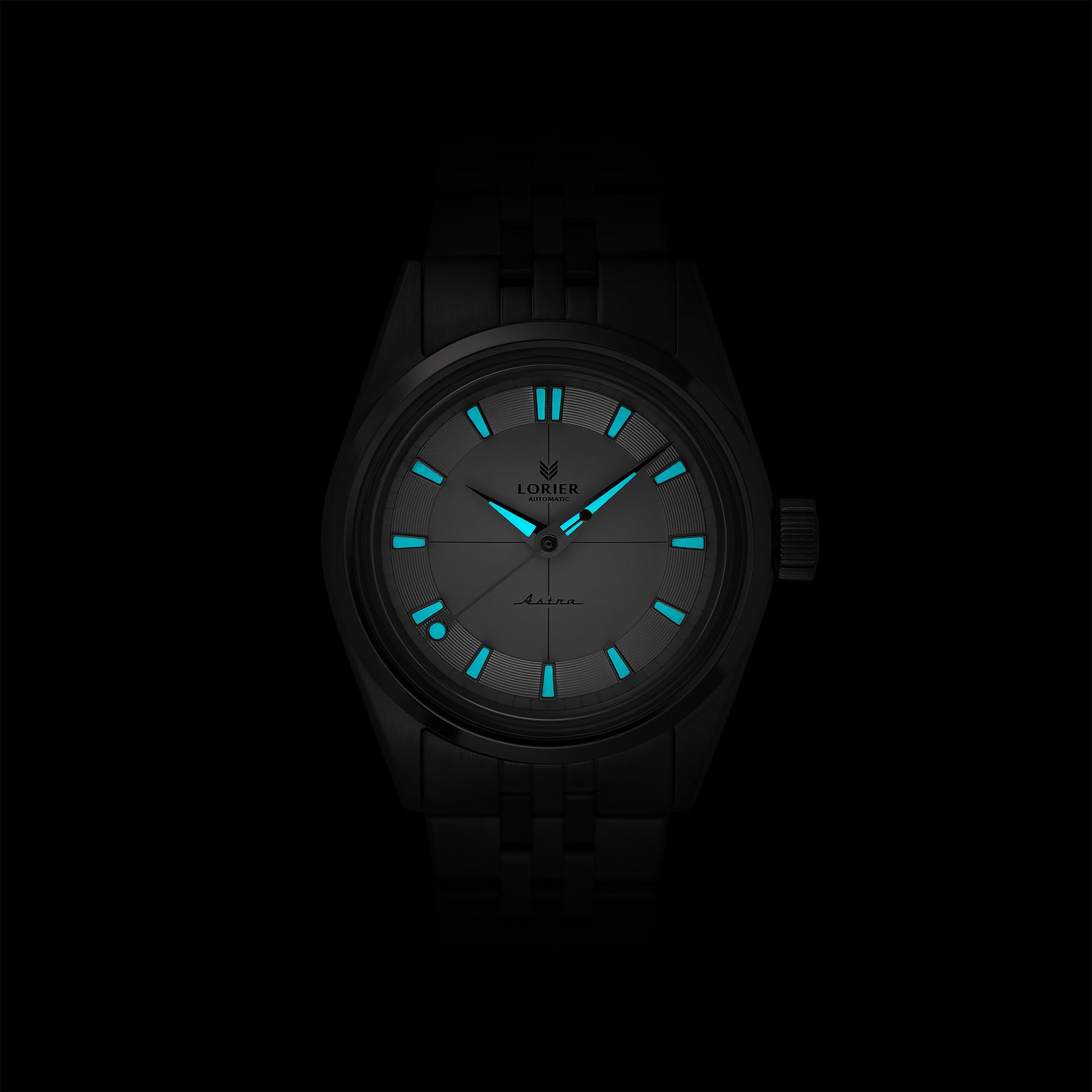 Lorier Astra automatic watch in darkness showing Superluminova lume on hands and dial glowing against black background.