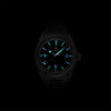 Lorier Falcon automatic watch in darkness showing Superluminova lume on Arabic numerals, baton hour markers, and handset glowing blue-green against black background.